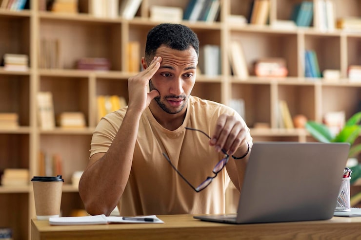 sad tired arab male freelancer working laptop touching head holding glasses looking computer screen 116547 42016